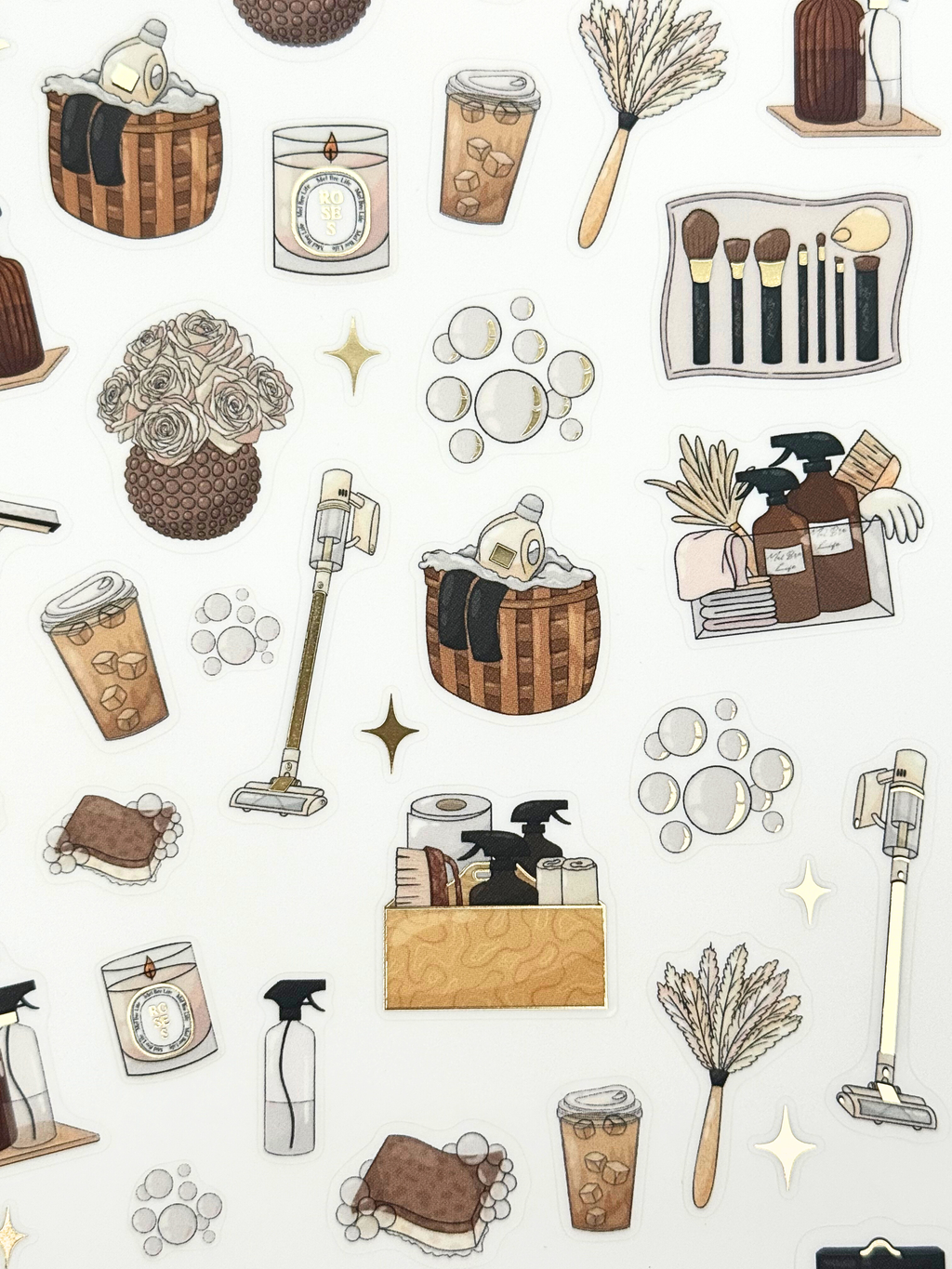 Clear matte glam planner sticker sheet with gold foil accents featuring cleaning supplies, baskets, sprays, and cozy home reset icons