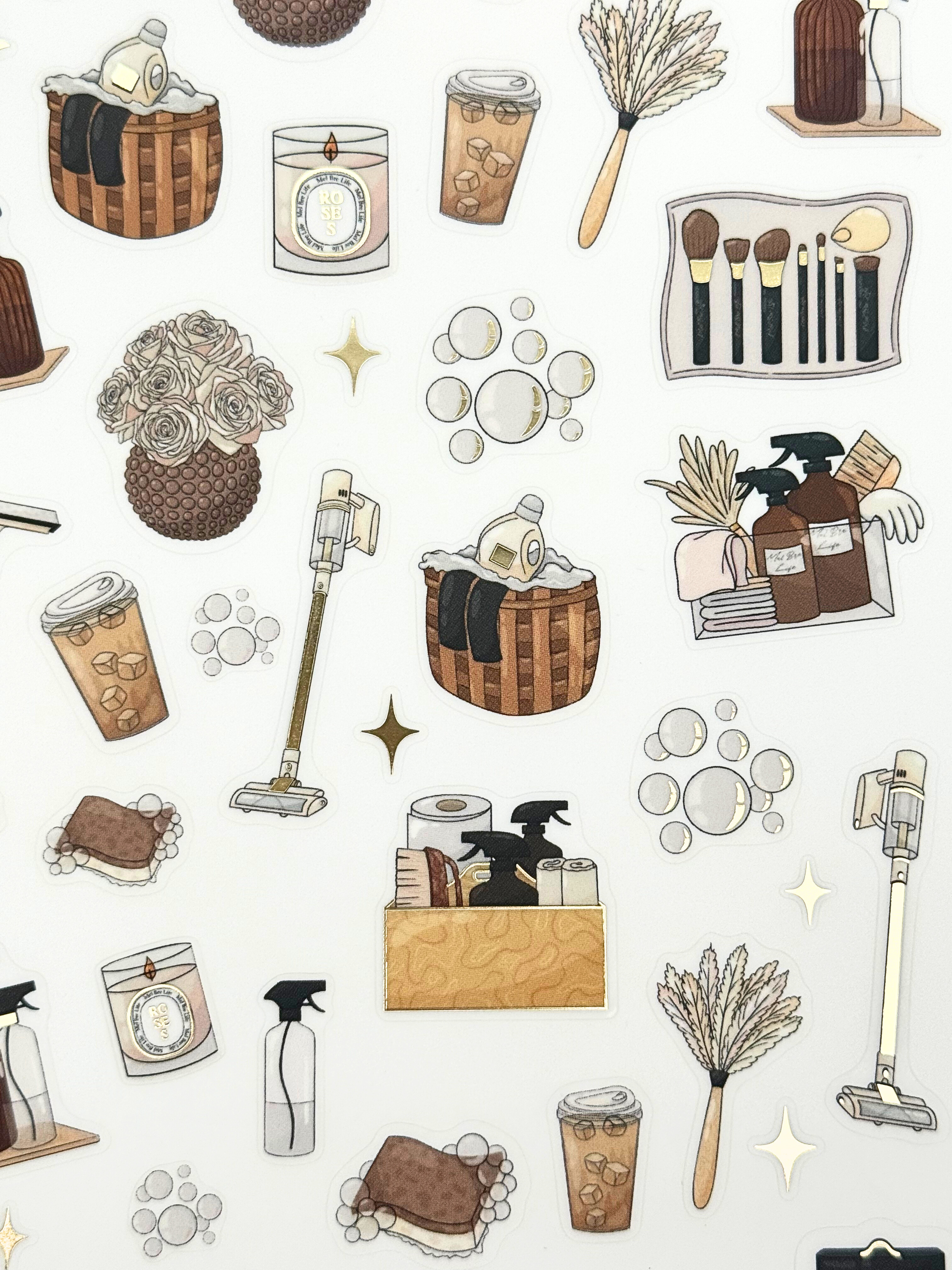 Clear matte glam planner sticker sheet with gold foil accents featuring cleaning supplies, baskets, sprays, and cozy home reset icons