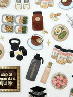 Clear matte glam planner sticker sheet with gold foil accents featuring wellness icons, workouts, meals, drinks, and habit tracking details