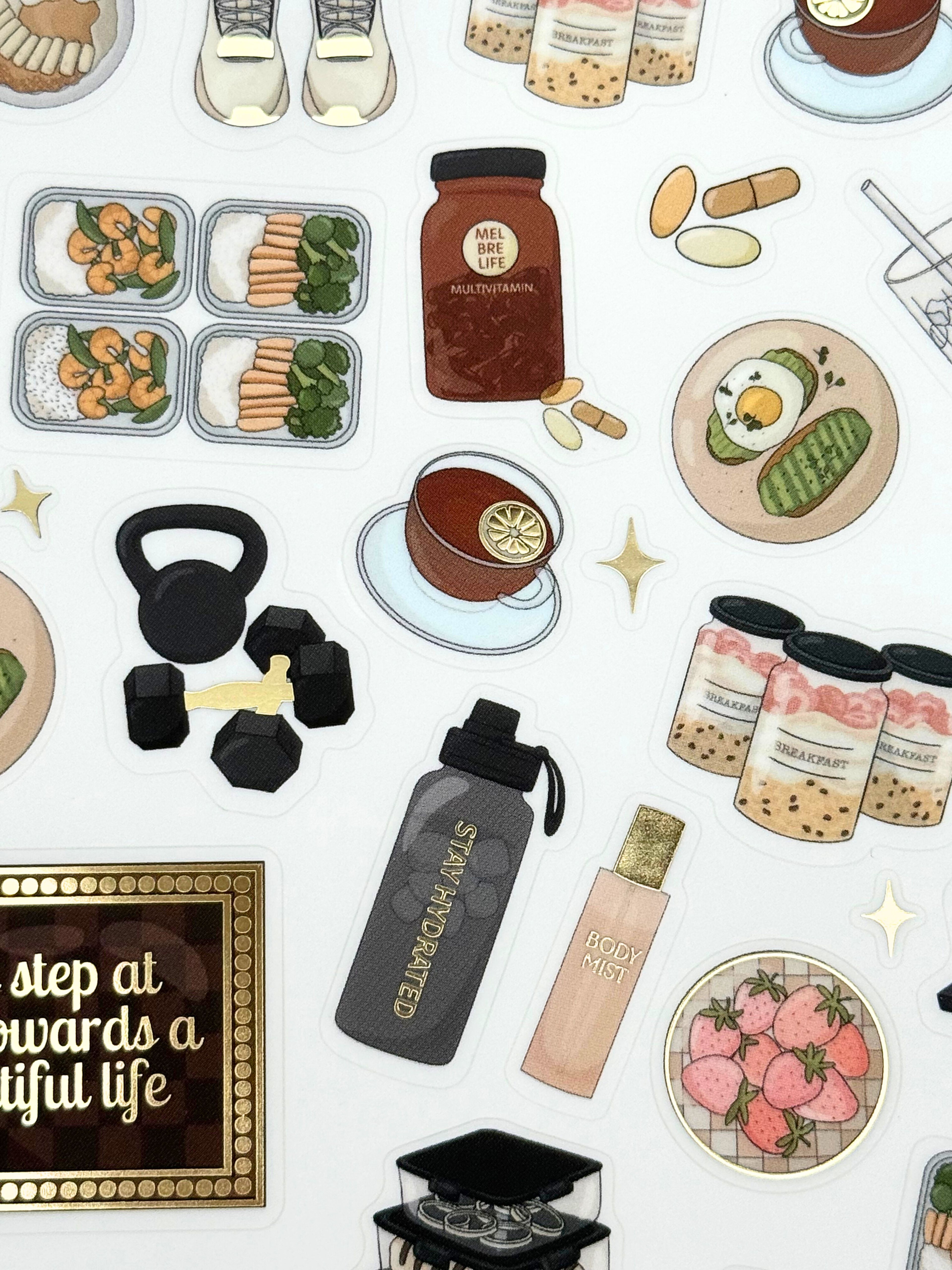 Clear matte glam planner sticker sheet with gold foil accents featuring wellness icons, workouts, meals, drinks, and habit tracking details