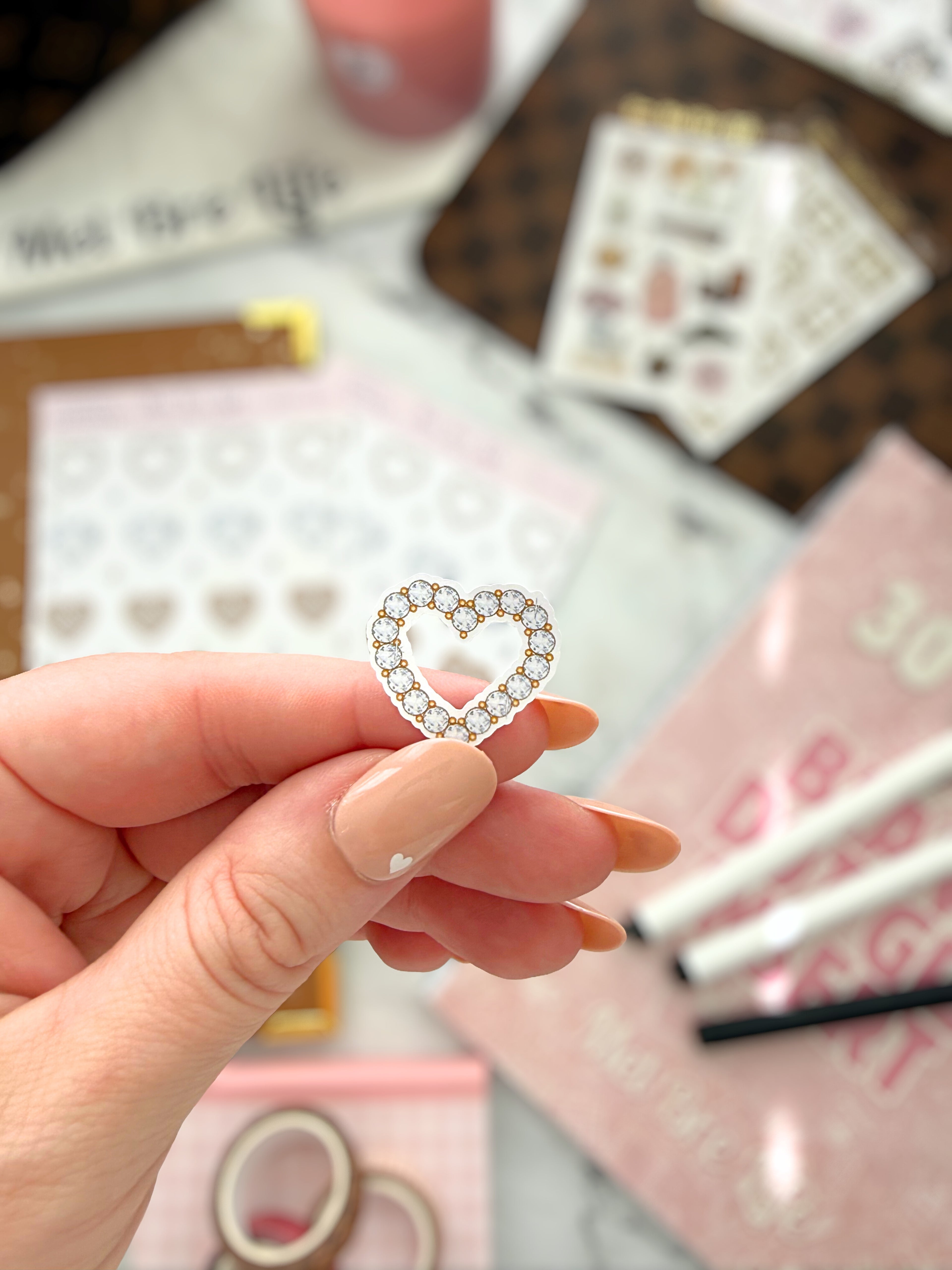 Heart-shaped earring held by a hand with a blurred background